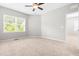 A bright bedroom featuring neutral walls, carpet flooring, a ceiling fan and a view of outdoors at 1007 Epiphany Rd, Morrisville, NC 27560