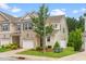 Townhouse featuring a well-maintained lawn, brick accents, a garage, and a charming tree in front at 1007 Epiphany Rd, Morrisville, NC 27560