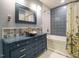 Stylish bathroom featuring a blue vanity, decorative mirror, and tub shower at 10101 Daviton Ct, Raleigh, NC 27615