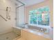 Soaking tub and glass enclosed shower with views of wooded area from large window at 10101 Daviton Ct, Raleigh, NC 27615