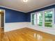 Dining room featuring half blue walls, wood flooring, and large windows at 10101 Daviton Ct, Raleigh, NC 27615