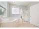 Bathroom featuring a large tub, walk-in shower, window, and neutral tile floors at 10847 Bedfordtown Dr, Raleigh, NC 27614