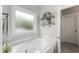 Bathroom with soaking tub under a window, decorative accessories, and tile floor at 10859 Bedfordtown Dr, Raleigh, NC 27614