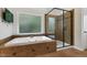 Relaxing bathroom features a large soaking tub, glass-enclosed shower, and a wall-mounted television at 109 Aspenridge Dr, Holly Springs, NC 27540