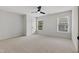 Spacious carpeted bedroom featuring a ceiling fan and natural light from two windows at 109 Aspenridge Dr, Holly Springs, NC 27540