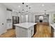 Bright kitchen with stainless appliances, quartz countertops, and large island opening up to the living room at 109 Aspenridge Dr, Holly Springs, NC 27540