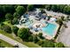 Aerial view of a community pool with water slides, seating, and a parking lot surrounded by lush trees at 109 Aspenridge Dr, Holly Springs, NC 27540
