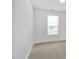 Empty bedroom with neutral carpet, a window overlooking a lush green view, and fresh white walls at 110 Knightwood Dr, Durham, NC 27703