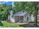 Home featuring a covered entryway, light siding, manicured landscaping, and mature trees at 1202 Kendall Dr, Durham, NC 27703