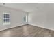 Spacious living room featuring two bright windows, light wood-look flooring, and freshly painted white walls at 1202 Kendall Dr, Durham, NC 27703