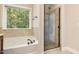 Bathroom showcasing a large tub, glass-enclosed shower, and natural light from a window at 1304 Barnford Mill Rd, Wake Forest, NC 27587