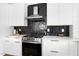 Modern kitchen with stainless steel appliances, white cabinets, quartz countertop, and black tiled backsplash at 1410 Joe Louis Ave, Raleigh, NC 27610