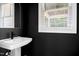 Modern powder room with a pedestal sink, black accent wall, and natural light at 1410 Joe Louis Ave, Raleigh, NC 27610