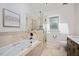 Bright bathroom with a tub and shower, travertine surround, and modern fixtures at 2008 Corberrie Ln, Raleigh, NC 27613