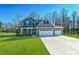 Charming two-story home featuring blue siding, stone accents, and a three-car garage on a manicured lawn at 21 Abingdon Farms Dr, Selma, NC 27576
