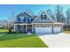 Charming two-story home featuring blue siding, stone accents, and a three-car garage on a manicured lawn at 21 Abingdon Farms Dr, Selma, NC 27576