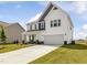 Two-story home with white siding, stone accents, covered porch, an attached two-car garage, and landscaped front yard at 218 Faith Avenue, Sanford, NC 27330
