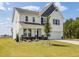 Two-story home with white siding, stone accents, covered porch, an attached two-car garage, and landscaped front yard at 218 Faith Avenue, Sanford, NC 27330