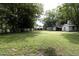 View of the home from the backyard showing the lush lawn, mature trees, and storage buildings at 219 E Nash St, Spring Hope, NC 27882
