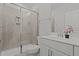 Well-lit bathroom featuring a glass enclosed tiled shower and single sink vanity with a decorative floral accent at 2346 Mckenzie Ridge Ln, Apex, NC 27502
