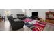 Comfortable living room featuring a modern area rug, entertainment center, and black leather sofa set at 2346 Mckenzie Ridge Ln, Apex, NC 27502