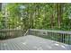 Outdoor deck with gray wooden flooring and a railing in a wooded setting at 2425 Lemuel Dr, Raleigh, NC 27615