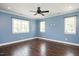 This bedroom boasts two large windows, hardwood floors, a ceiling fan, and blue paint at 2508 Kearney Rd, Wake Forest, NC 27587