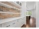 Charming butler's pantry with brick backsplash, white cabinets, marble counters, and open shelving at 2508 Kearney Rd, Wake Forest, NC 27587