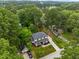 This aerial view showcases a home with mature trees, lush landscaping, a paved driveway and a covered porch at 2551 Drake Ave, Durham, NC 27705
