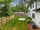 A spacious backyard featuring a well-maintained lawn, tall trees and a wooden fence offers privacy and outdoor enjoyment at 2551 Drake Ave, Durham, NC 27705
