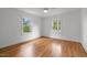 Bright bedroom featuring hardwood floors, white walls, two windows, and a ceiling fan at 2551 Drake Ave, Durham, NC 27705