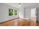 Light bedroom with hardwood floors, built-in shelving, a ceiling fan, and large windows with outdoor views at 2551 Drake Ave, Durham, NC 27705