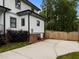 Wide concrete driveway leading to a wooden fence, complemented by the home's white siding and black window trim at 2551 Drake Ave, Durham, NC 27705