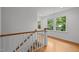 Upstairs hallway featuring hardwood floors, natural lighting, and white wooden trim accents throughout at 2551 Drake Ave, Durham, NC 27705