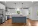 Bright kitchen featuring white cabinets, stainless steel appliances, hardwood floors, and a blue kitchen island at 2551 Drake Ave, Durham, NC 27705