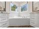 Bright bathroom featuring a soaking tub with tile surround, undermount sink and a view from the window at 3034 Lewis Farm Rd, Raleigh, NC 27607