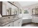 Bright bathroom with dual sink vanity, granite countertops, and a soaking tub under a window at 3034 Lewis Farm Rd, Raleigh, NC 27607