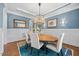 Elegant dining room features a wooden table, six chairs, blue walls, and a modern chandelier at 3034 Lewis Farm Rd, Raleigh, NC 27607