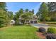 Inviting home exterior with a lush lawn, mature tree, and ample driveway space at 3034 Lewis Farm Rd, Raleigh, NC 27607