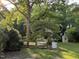 Lush backyard featuring garden, large shade tree, and additional small out-building in a wooded setting at 313 W Noble St, Louisburg, NC 27549