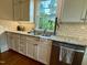Well-lit kitchen featuring granite countertops, subway tile, and stainless steel dishwasher at 313 W Noble St, Louisburg, NC 27549