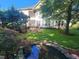 Scenic backyard featuring a charming pond with lush landscaping and a screened porch at 502 Willowmere Ct, Cary, NC 27513