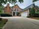 View of a brick home with an attached two-car garage and well-manicured landscaping at 502 Willowmere Ct, Cary, NC 27513