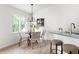 Bright dining area with modern chandelier, woven chairs and sunlit window, adjacent to the kitchen bar for easy serving at 522 Johnson St, Garner, NC 27529