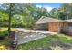 View of the large carport with brick columns and concrete driveway, surrounded by mature trees and green lawn at 5414 Ventoria Rd, Durham, NC 27712