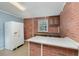 Kitchen featuring brick walls, white fridge, and a window for natural light at 5917 Meadowlark Ln, Raleigh, NC 27610