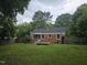 View of backyard with wooden fence and red brick house featuring a wood deck and small covered porch at 704 N King Charles Rd, Raleigh, NC 27610