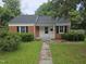 Charming single-story brick home with white trim, black shutters, and a well-maintained front lawn at 704 N King Charles Rd, Raleigh, NC 27610