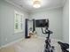 Brightly lit bonus room with exercise equipment, TV, and full length mirror at 7906 Longleaf Branch Ct, Raleigh, NC 27612
