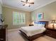 Comfortable bedroom with neutral carpet, a ceiling fan, and a shuttered window at 7906 Longleaf Branch Ct, Raleigh, NC 27612